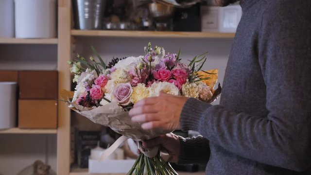 Close up florist hands. man making bunch at flower shop. people, business, sale and floristry concept. Bouquet with roses, peone, lilac and lisianthus