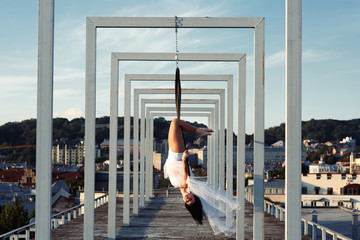 Sexy strong dancer performing on aerial hoop on rooftop