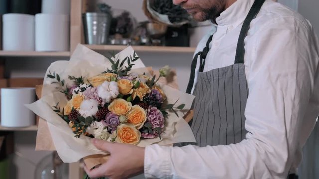 Close up florist hands. man making bunch at flower shop. people, business, sale and floristry concept. Bouquet with roses, peone, lilac and lisianthus