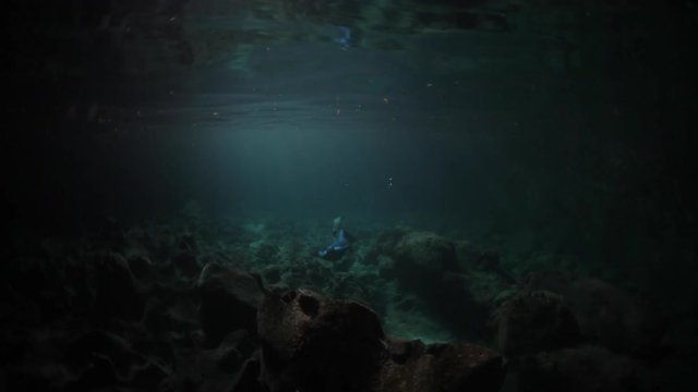 Underwater shoot of freediver swimming inside the underwater cave. High level of noise, iso 800