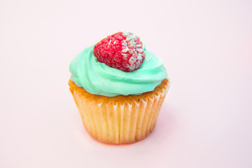 Cupcakes with butter cream and vanilla with raspberry on pink background