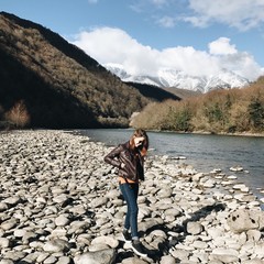 девушка гуляет у реки в горах