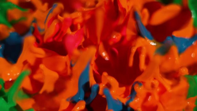 A neon rainbow of paint dances on top of a pulsing speaker in slow motion