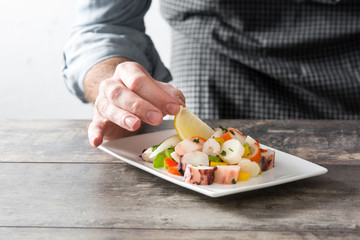 Chef preparing seafood ceviche on wooden table

