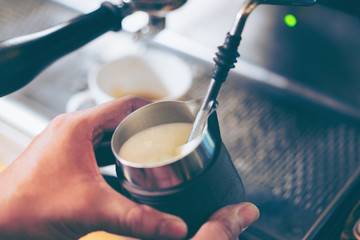 Barista using coffee machine preparing fresh coffee or latte art
