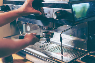 Barista using coffee machine preparing fresh coffee or latte art