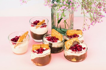 Six bowl with chocolate and vanilla puding and vase with flower.