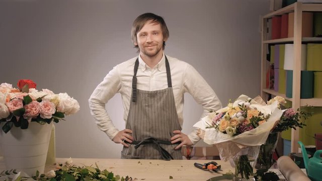 Photo of smiling florist standing with a colorful bouquet in flower shop. Bouquet with roses, peone, lilac and lisianthus
