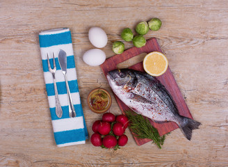 dorado fish, radishes, eggs, spices and brussels sprouts on a rustic table