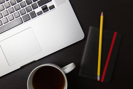 Laptop Computer, Coffee Cup And Notebook On Black Desktop