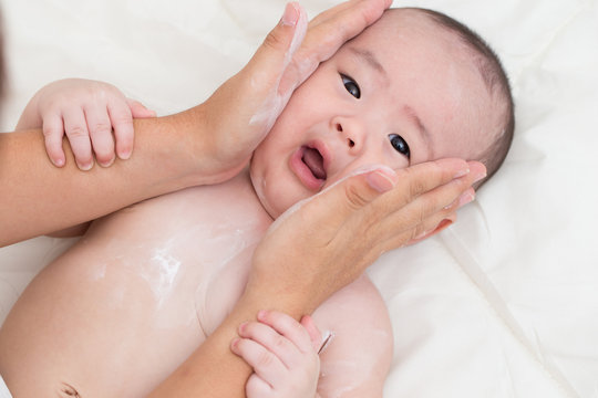Mother applying baby powder for son