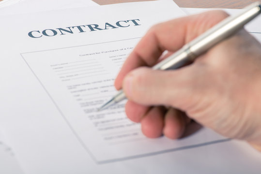 man's hand with a pen sign a contract