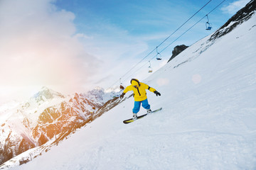 Man rides his snowboard on ski slope in winter mountains, in ski resort