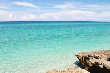 Fototapeta na wymiar Морской пейзаж - яркое лазурное Карибское море, кучевые облака и скалистый берег. Фото сделано на Кубе.