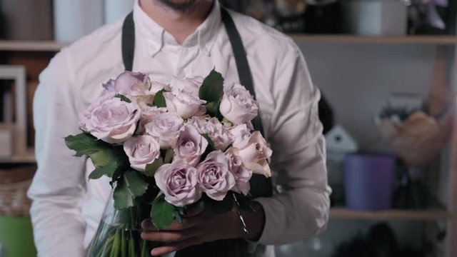 Close up view of florist preparing flower composition at workplace,bouquet of roses peone and lilac for valentine's day and women's day