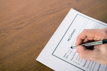 man's hand with a pen sign a contract