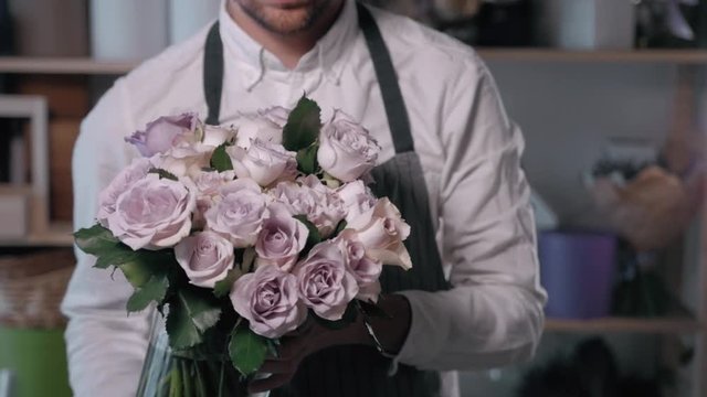 Close up view of florist preparing flower composition at workplace,bouquet of roses peone and lilac for valentine's day and women's day