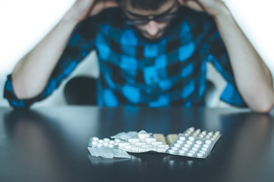 Junger Mann, Tabletten auf dem Tisch, Drogensucht