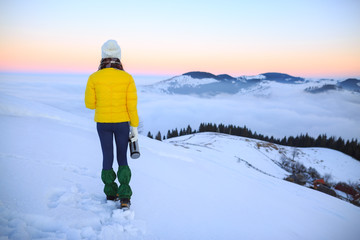 Young woman hiking in winter mountains. Woman drinking warm tea in the mountai.