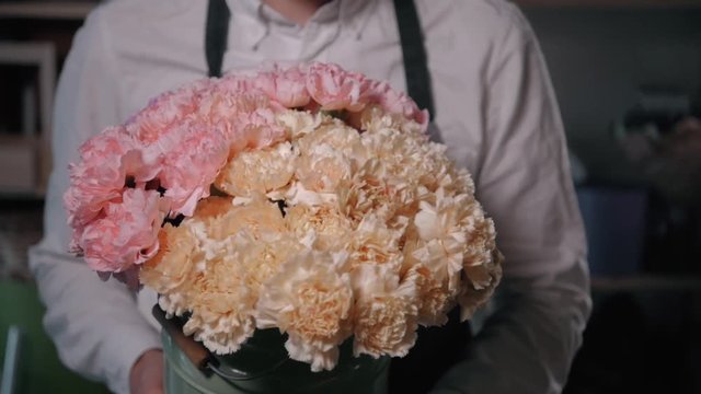 Close up view of florist preparing flower composition at workplace,bouquet of roses peone and lilac for valentine's day and women's day