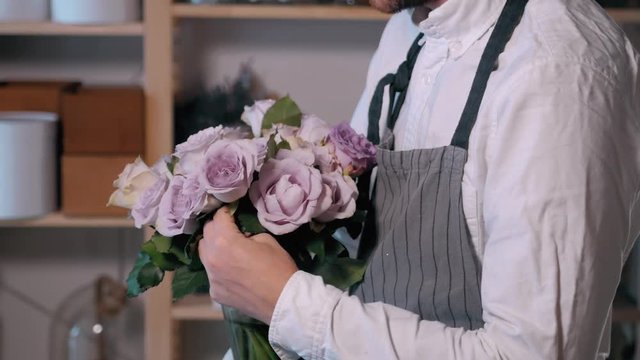 Close up florist hands. man making bunch at flower shop. people, business, sale and floristry concept. Bouquet with roses, peone, lilac and lisianthus