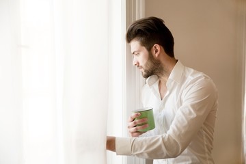 A young adult man at home drinking coffee..