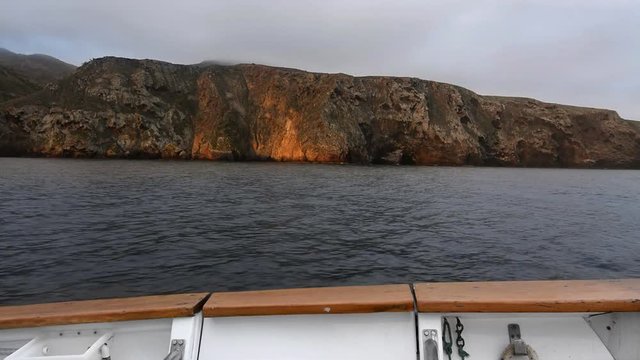 A view over a boats port side shows the side of an island during a morning sunrise. Shot with a Nikon D7100 24mp camera at f8, shutter speed 30..