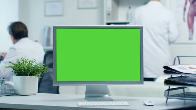 Close-up of a Monitor with Green Screen. Doctor Works with Folders, Assistant Talks with Patients on the Phone. Shot in a Bright and Modern Doctor's Office. Shot on RED Cinema Camera 4K (UHD).