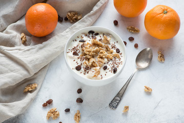 Gesundes Frühstück mit Joghurt, Orangen, Walnüssen, Rosinen und Leinsamen
