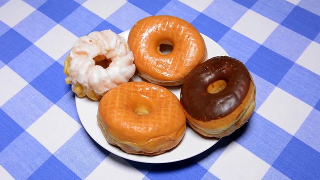 A man grabs a donut from a plate of donuts, takes a bite then puts it back on the plate.