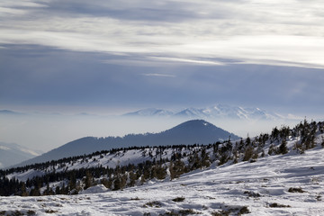 Winter mountains and sunlight cloudy sky in haze