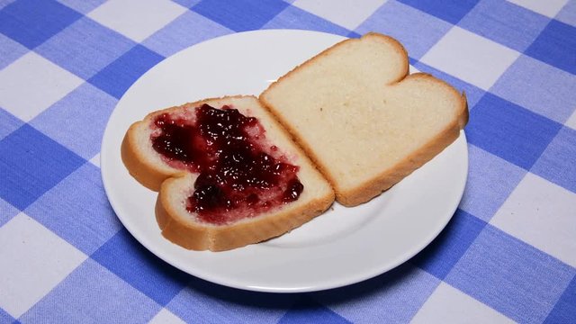 A woman makes a classic peanut butter and jelly sandwich on fresh white bread.