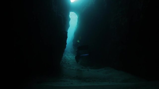 Underwater shoot of freedivers swimming through the underwater canyon. High level of noise, iso 800
