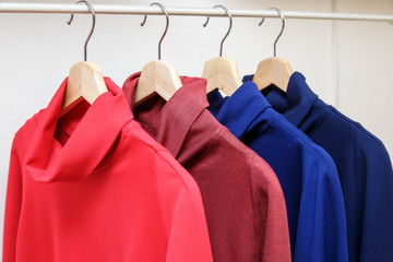 Rainbow colors. Choice of casual clothes on wooden hangers in a store