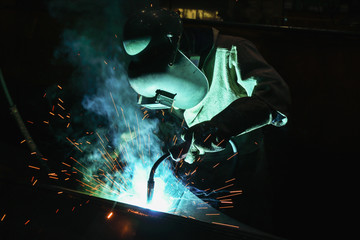 Welder of Metal Welding with sparks and smoke from manufacturing
