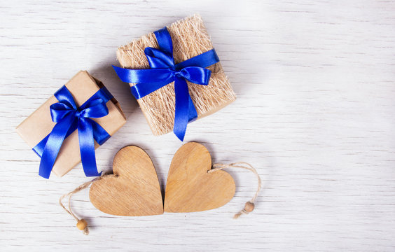 Two gift boxes with blue ribbons and wooden hearts on a white background. Valentine's Day. Copy space. 