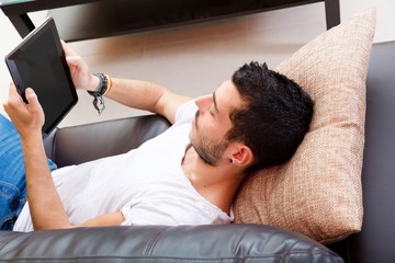 Portrait of a young man relaxing on a couch with a tablet..