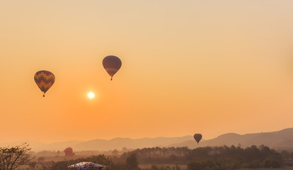 The silhouette of balloon floating in the sky above the mountain