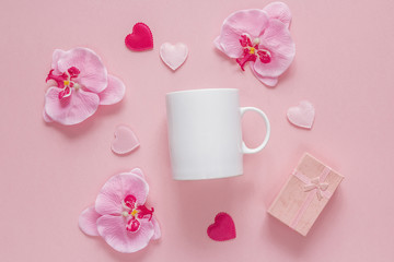 White coffee mug with orchid flowers, gift box and hearts on a p