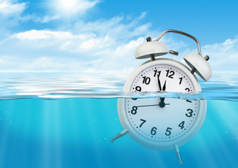 Alarm clock in water, waste of time concept