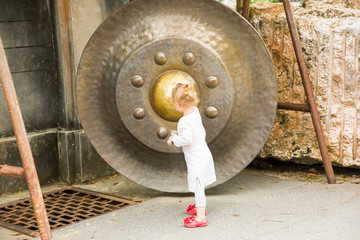 Child near Thai gong in Phuket. Tradition asian bell in Buddhism temple in Thailand. Famous Big bell wish near Gold Buddha
