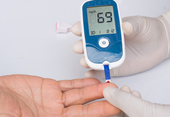 Measuring blood sugar on finger of old woman with diabetes