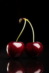Two juicy fresh cherries on black background
