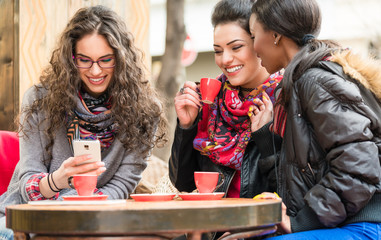 Women in cafe showing pictures on smart phone