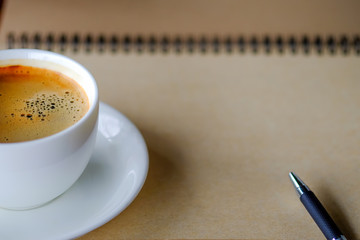 Pen on notebook with coffee.