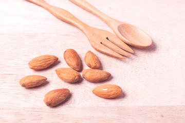 Almonds in brown bowl on wooden background