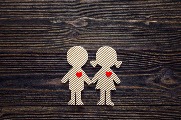 Cardboard silhouettes girl and boy with hearts on a wooden table