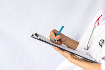 Doctor holding stethoscope and writing treat report on clipboard