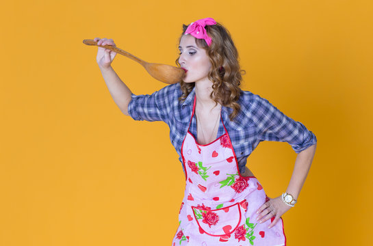 Gorl holding a spoon near a mouth to taste a food