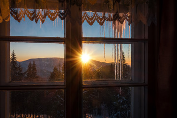 Looking through window at mountain winter sunset